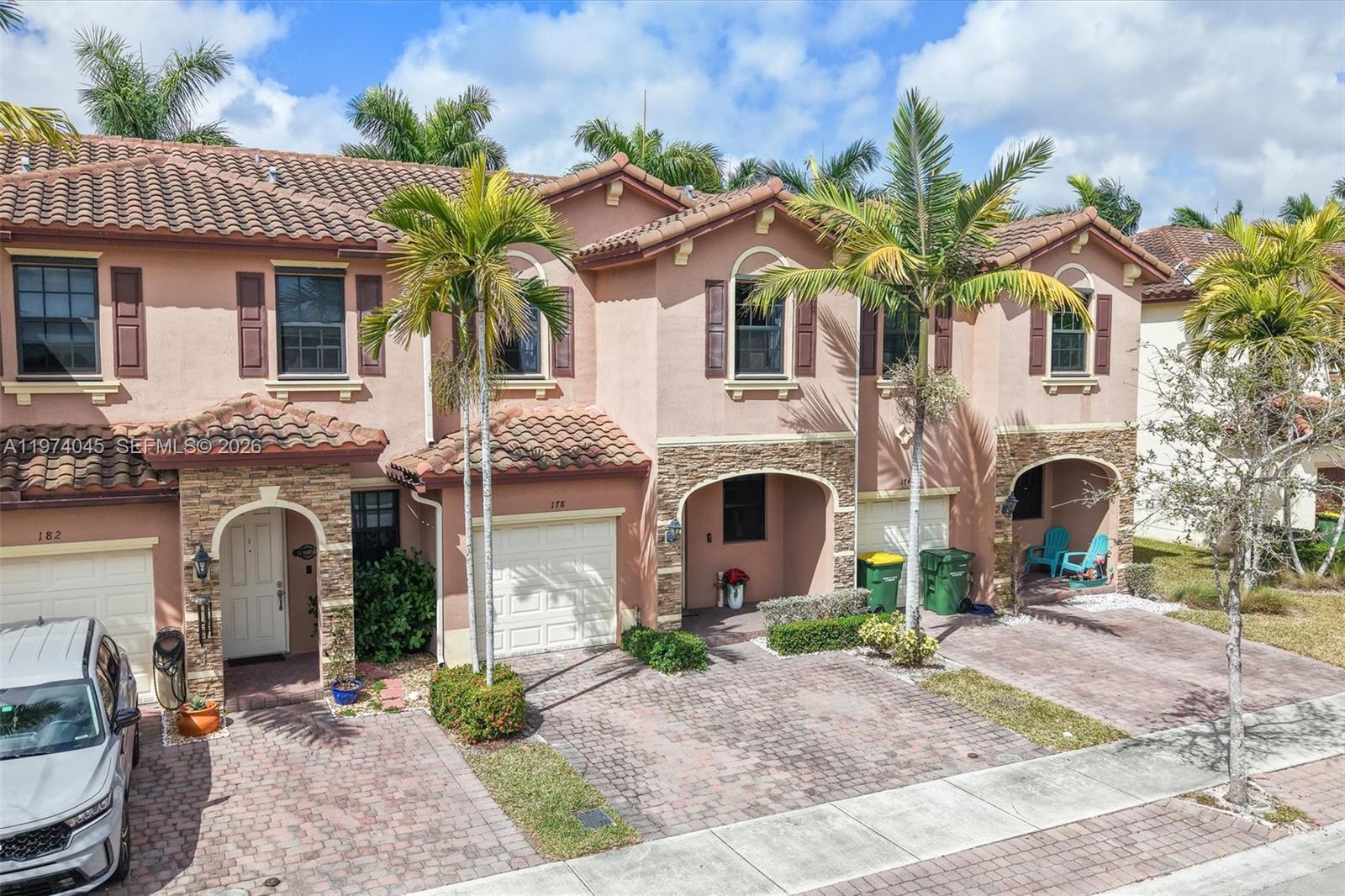 A row of three-story townhouses with stucco facades, tile roofs, and paved driveways — 178 SE 33rd Ter, Homestead FL 33033, HOMESTEAD, FL