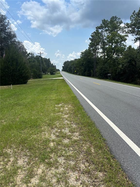A paved road stretches into the distance past a grassy shoulder and wooded area — 4035 N HIGHWAY 314A UNIT 2, SILVER SPRINGS, FL