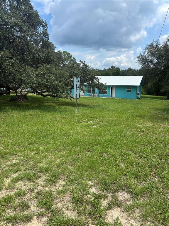 A turquoise house with a white metal roof sits on a large, grassy lot — 4035 N HIGHWAY 314A UNIT 2, SILVER SPRINGS, FL