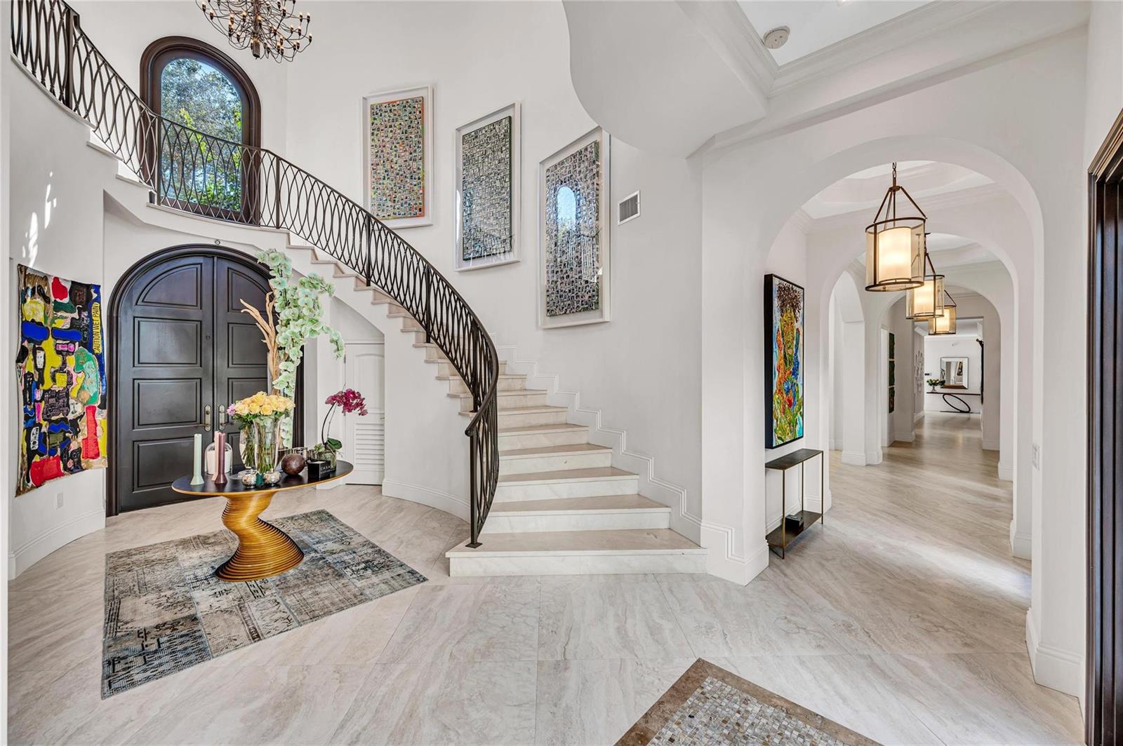 A grand foyer features a curved staircase, marble flooring, and a dark wood arched door — 4955 SW 83rd Street, Miami FL 33143, MIAMI, FL