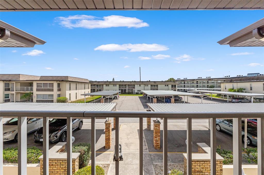 A view from a balcony overlooking a parking lot with covered carports and apartment buildings — 5111 AMULET DRIVE UNIT 202, NEW PORT RICHEY, FL