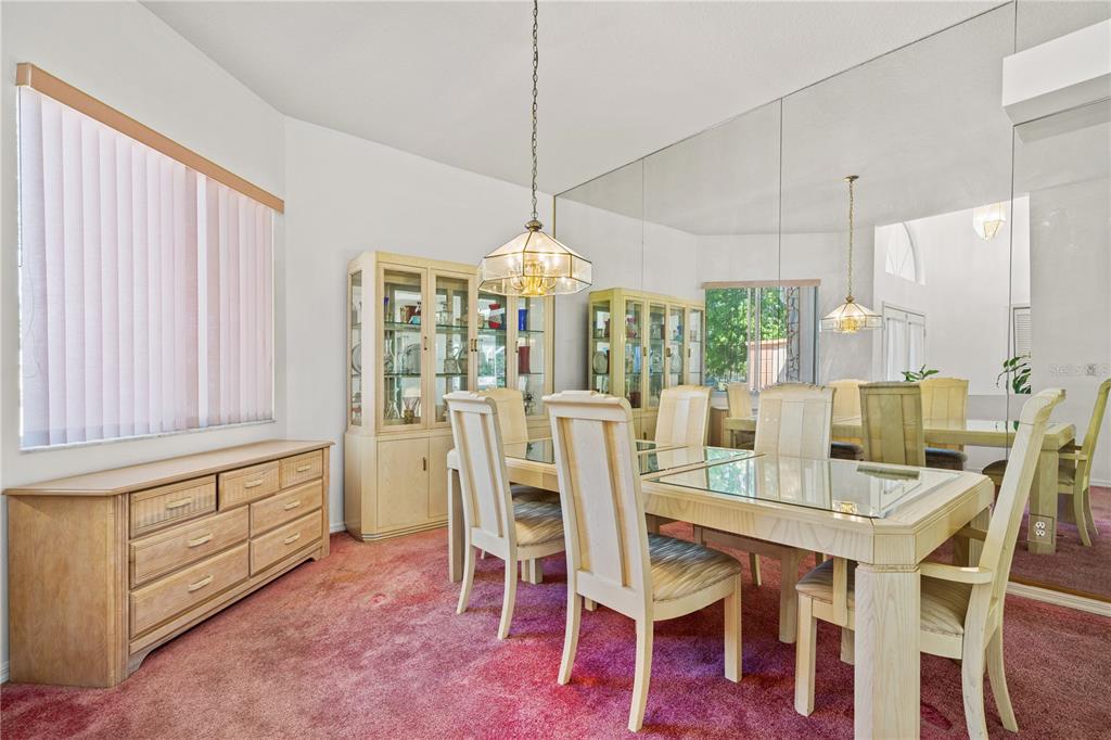 A dining room features a glass-topped table, light wood furniture, pink carpet, and mirrored walls — 4071 BLACK OAK TRAIL, BROOKSVILLE, FL