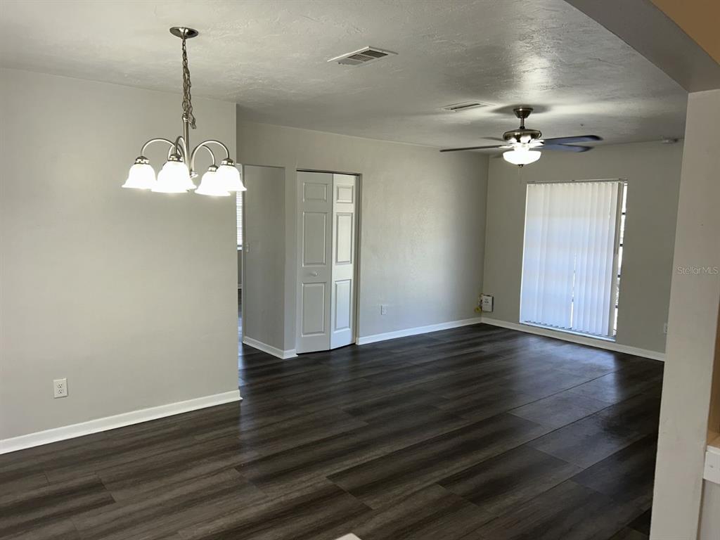 A dining and living area features gray walls, dark wood-look flooring, and a ceiling fan — 1241 PILGRIM RD, SPRING HILL, FL