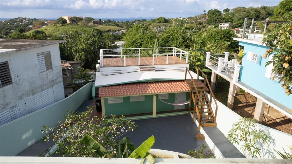 An elevated view of a green house with a wooden rooftop deck and exterior stairs — E115 CALLE M-GARCIA, VIEQUES, PR