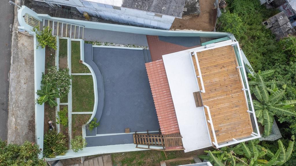 An aerial view shows a backyard with a patio, tiered landscaping, and a wooden deck — E115 CALLE M-GARCIA, VIEQUES, PR