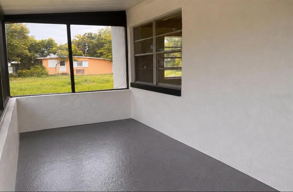 A screened-in porch with white walls, a gray painted floor, and a large window — 1718 KENTUCKY AVENUE, ST CLOUD, FL