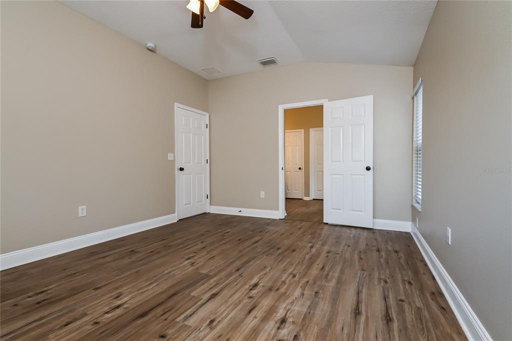 An empty bedroom features light-colored walls, wood-look flooring, a ceiling fan, and white doors — 2221 MOUNTAIN MEADOW WAY, VALRICO, FL