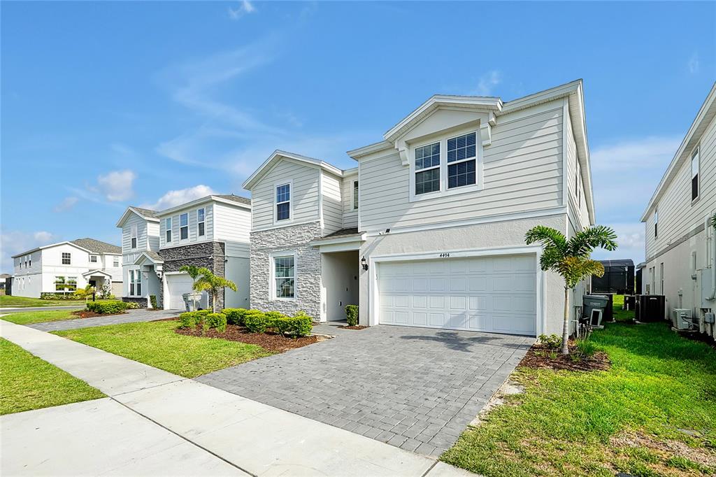 A two-story suburban house with a stone facade, white siding, and a paved driveway — 4494 KAIPO ROAD, DAVENPORT, FL
