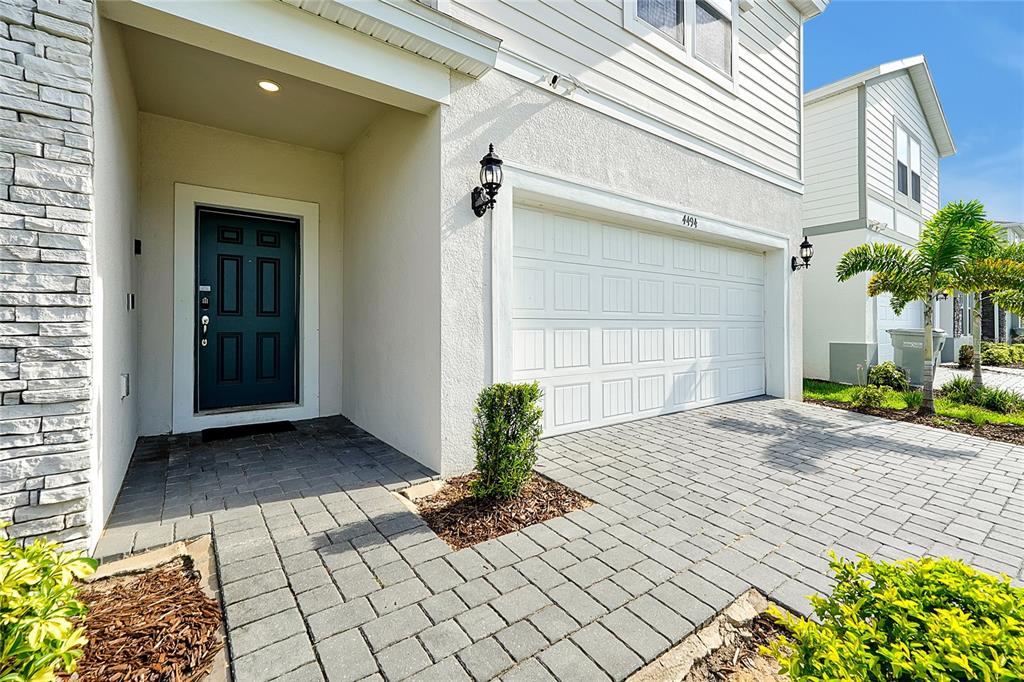 A two-story house exterior features a paved driveway, a white garage door, and a dark door — 4494 KAIPO ROAD, DAVENPORT, FL