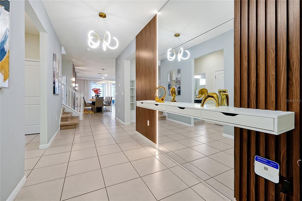 A modern hallway features tile flooring, a floating white console, and a large wall mirror — 4494 KAIPO ROAD, DAVENPORT, FL