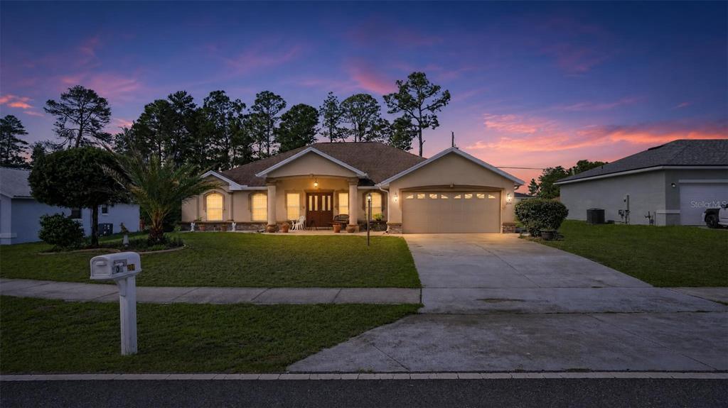 A single-story house with a beige stucco exterior, a two-car garage, and a manicured lawn — 208 MARION OAKS TRAIL, OCALA, FL