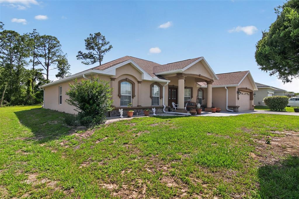 A tan, single-story house with a covered front porch and a two-car garage — 208 MARION OAKS TRAIL, OCALA, FL