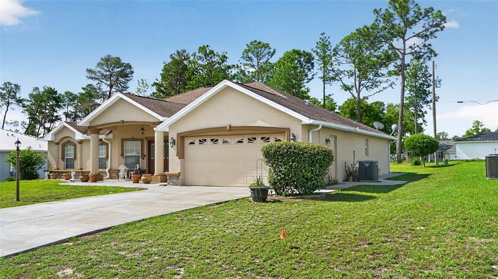 A single-story house with a beige stucco exterior, a two-car garage, and a front porch — 208 MARION OAKS TRAIL, OCALA, FL