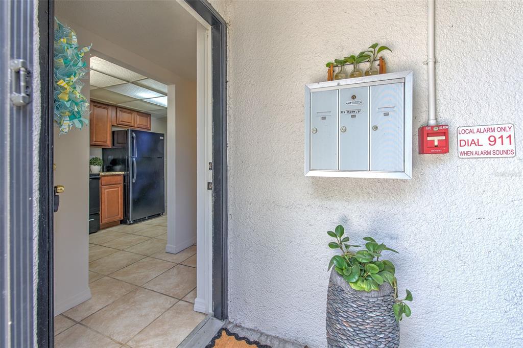 An open doorway reveals a kitchen with dark appliances and tile flooring next to mailboxes — 711 RUSSELL LANE UNIT 134, BRANDON, FL