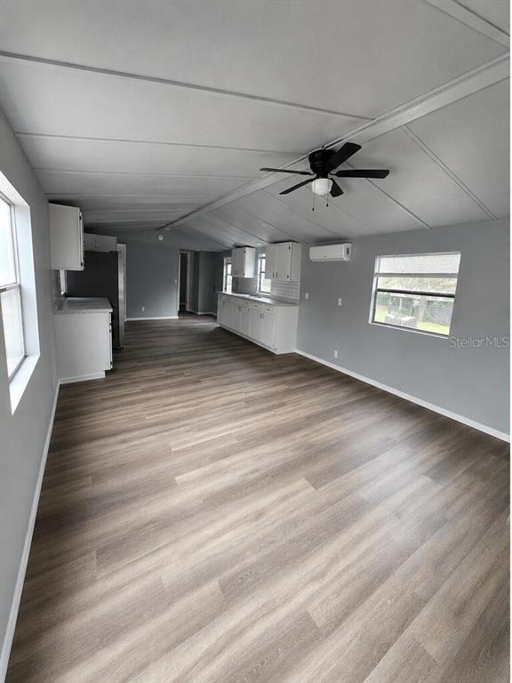 A kitchen and living area with light wood-look flooring, white cabinets, and a ceiling fan — 13585 SE 119TH STREET, OCKLAWAHA, FL