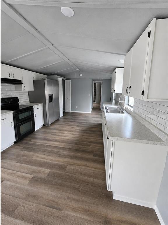 A kitchen with white cabinets, stainless steel appliances, a tiled backsplash, and wood-look flooring — 13585 SE 119TH STREET, OCKLAWAHA, FL