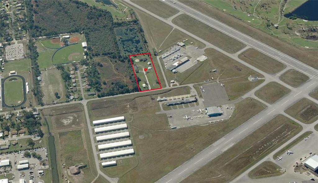 This aerial view shows a rectangular property lot outlined in red adjacent to an airport — 2804 PATRICK STREET, KISSIMMEE, FL