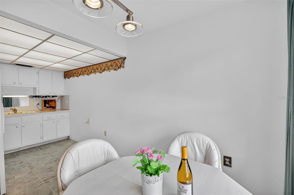 A dining area features a round table with chairs, a wet bar, and overhead lighting — 11100 86TH AVENUE UNIT 108, SEMINOLE, FL