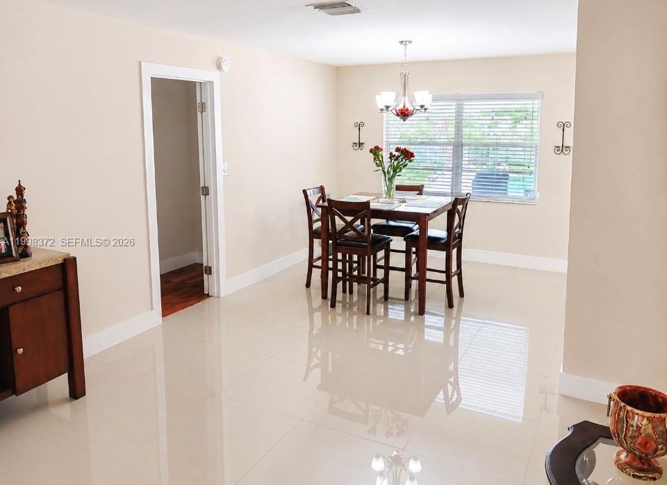 A dining room features a wooden table with four chairs, a chandelier, and tile flooring — 146 BONFIRE, Palm Bay FL 32907, PALM BAY, FL