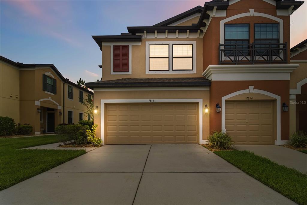 A two-story residential building with two garage doors and a balcony at dusk — 7856 52ND TERRACE E, BRADENTON, FL