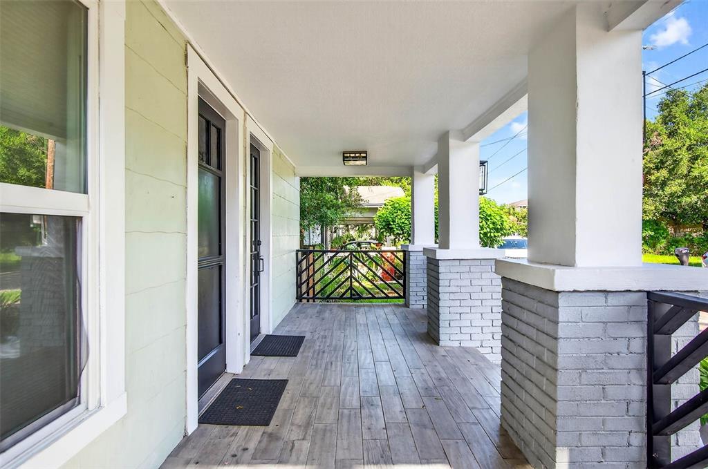 A covered front porch features wood-look tile flooring, gray brick columns, and a black railing — 809 E BAKER STREET UNIT A, TAMPA, FL