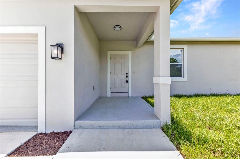 The exterior view shows a covered concrete entryway with a light-colored front door — 420 HOFFER STREET, PORT CHARLOTTE, FL