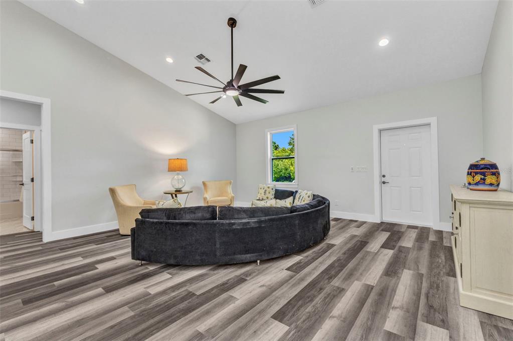 A living room with a curved dark sofa, two armchairs, and wood-look vinyl flooring — 420 HOFFER STREET, PORT CHARLOTTE, FL