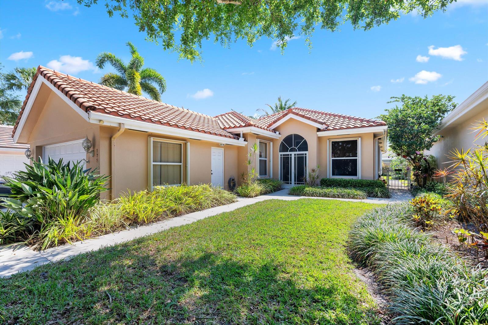 A single-story house with a tan exterior, tile roof, and a front lawn — 178 Hampton Place, Jupiter FL 33458, JUPITER, FL