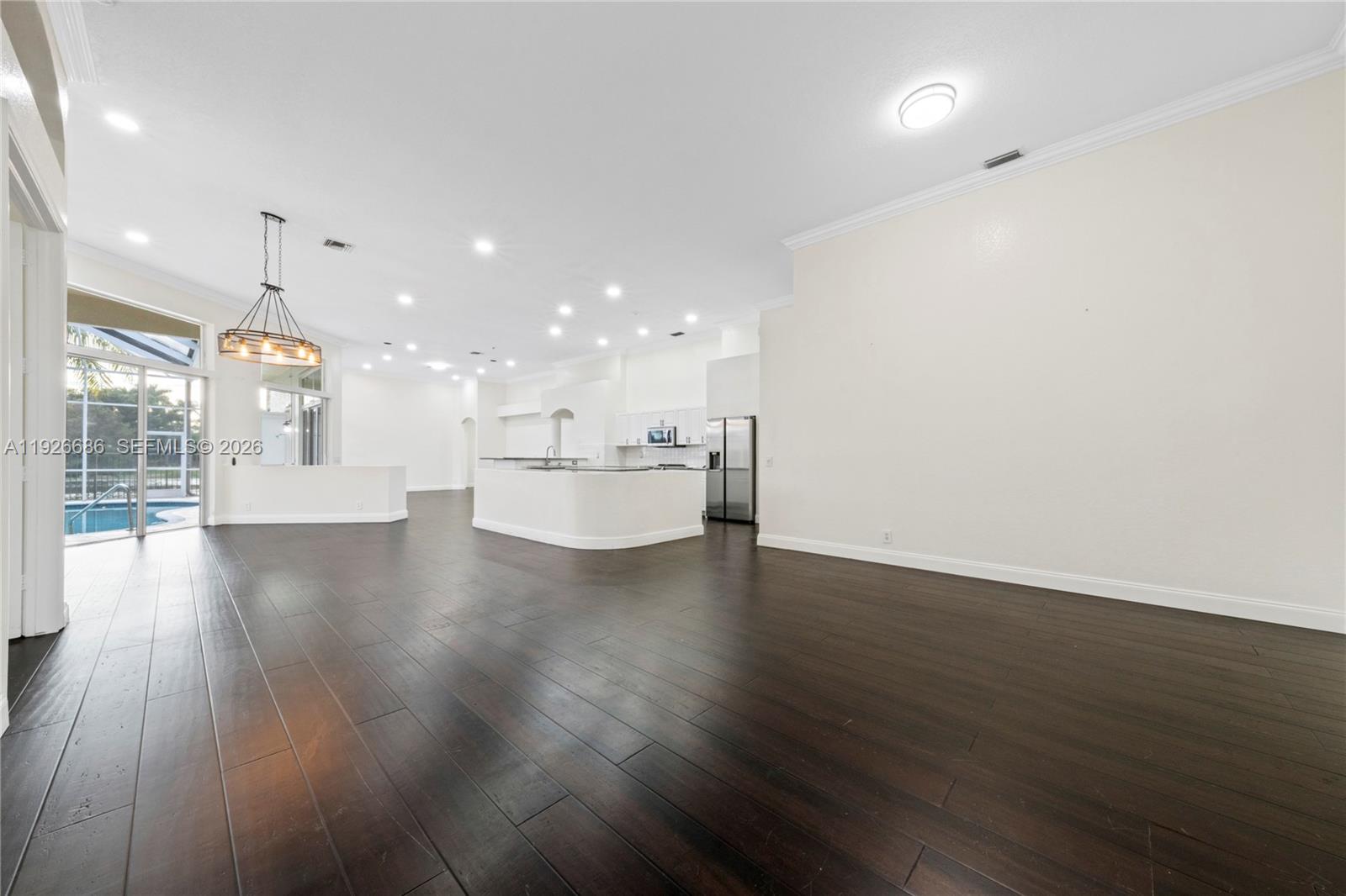 A spacious open-concept kitchen and living area features dark wood floors and white cabinetry — 2893 Oakbrook Dr, Weston FL 33332, WESTON, FL