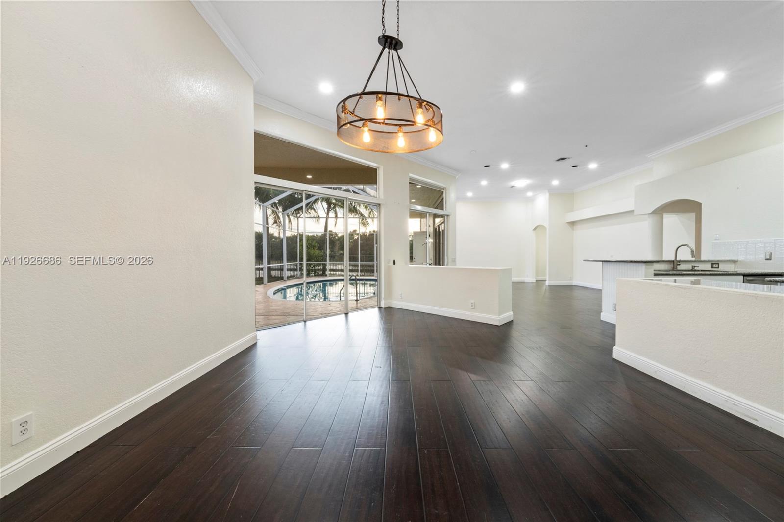An open-concept living area features dark wood flooring, a chandelier, and a view of a pool — 2893 Oakbrook Dr, Weston FL 33332, WESTON, FL