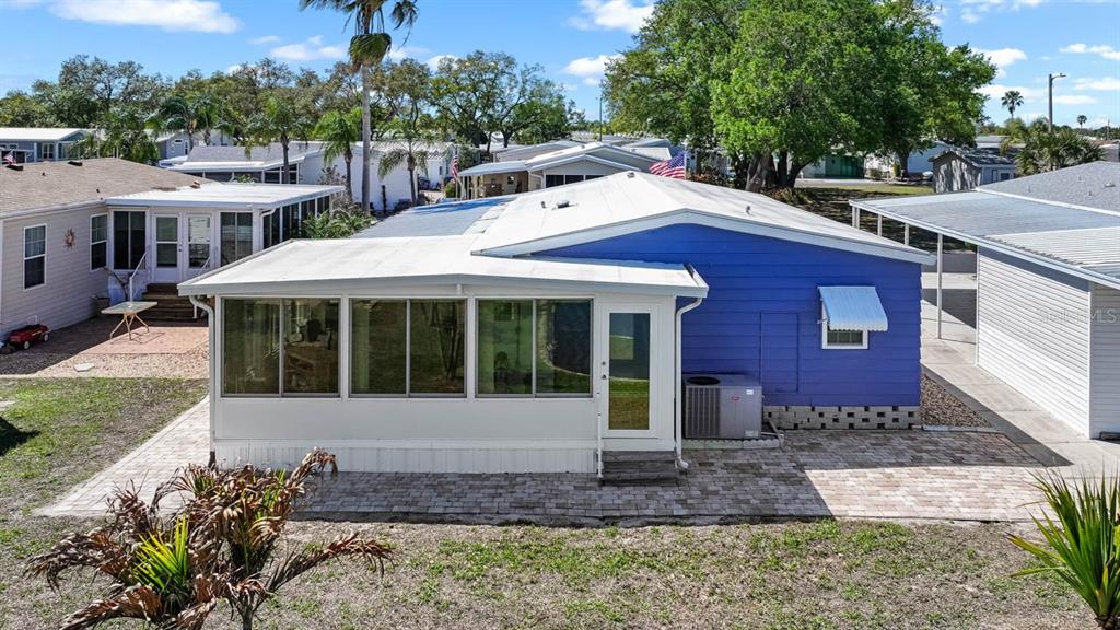 A blue mobile home with a white sunroom and a paved patio area — 101 SAINT GEORGE COURT, APOLLO BEACH, FL
