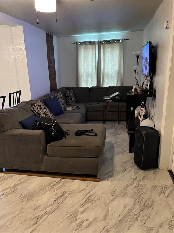 A living room features a large gray sectional sofa, marble-look tile flooring, and a wall-mounted television — 2440 WEBER STREET, LAKELAND, FL