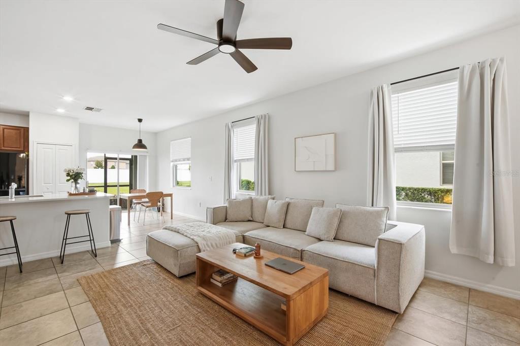 A living room features a sectional sofa, a wooden coffee table, and a ceiling fan — 7656 GINGER LILY COURT, TAMPA, FL