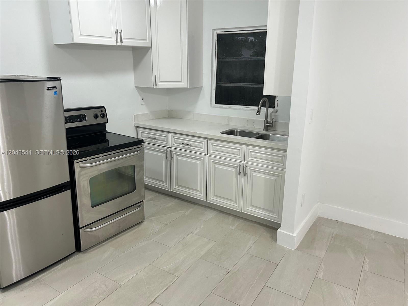 A kitchen features white cabinets, stainless steel appliances, a sink, and light-colored tile flooring — 261 NW 49th St # C, Miami FL 33127, MIAMI, FL
