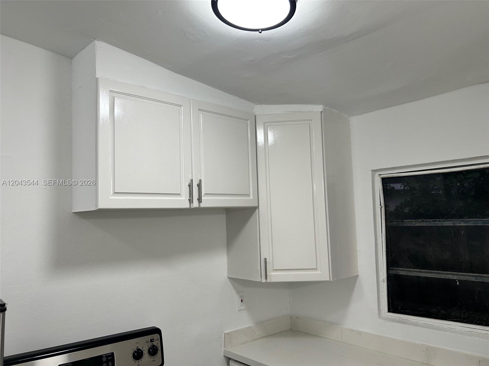 White kitchen cabinets are mounted on the wall above a countertop and stove — 261 NW 49th St # C, Miami FL 33127, MIAMI, FL