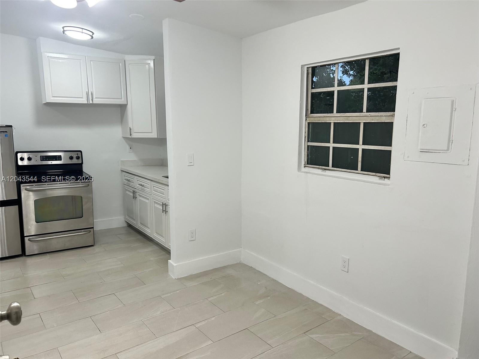 A kitchen features white cabinets, stainless steel appliances, and light-colored tile flooring — 261 NW 49th St # C, Miami FL 33127, MIAMI, FL
