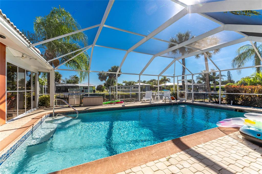 A swimming pool enclosed by a screened lanai with a patio and palm trees — 180 PURDY DRIVE, PUNTA GORDA, FL
