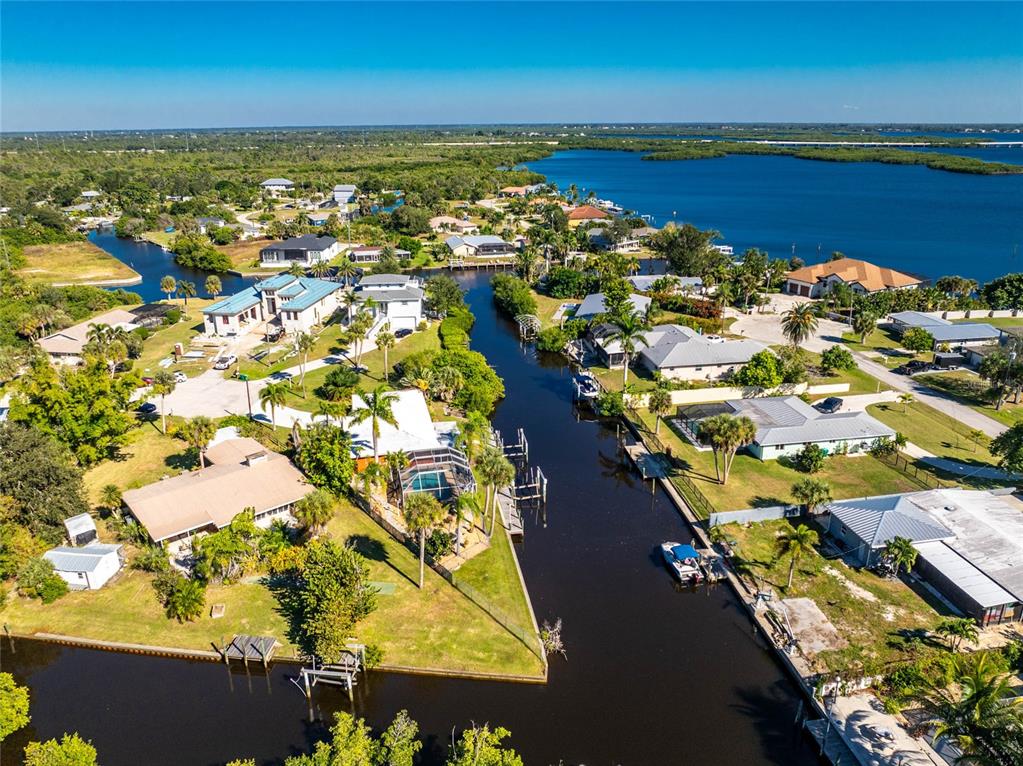 An aerial view shows waterfront homes along a canal leading to a large open bay — 180 PURDY DRIVE, PUNTA GORDA, FL