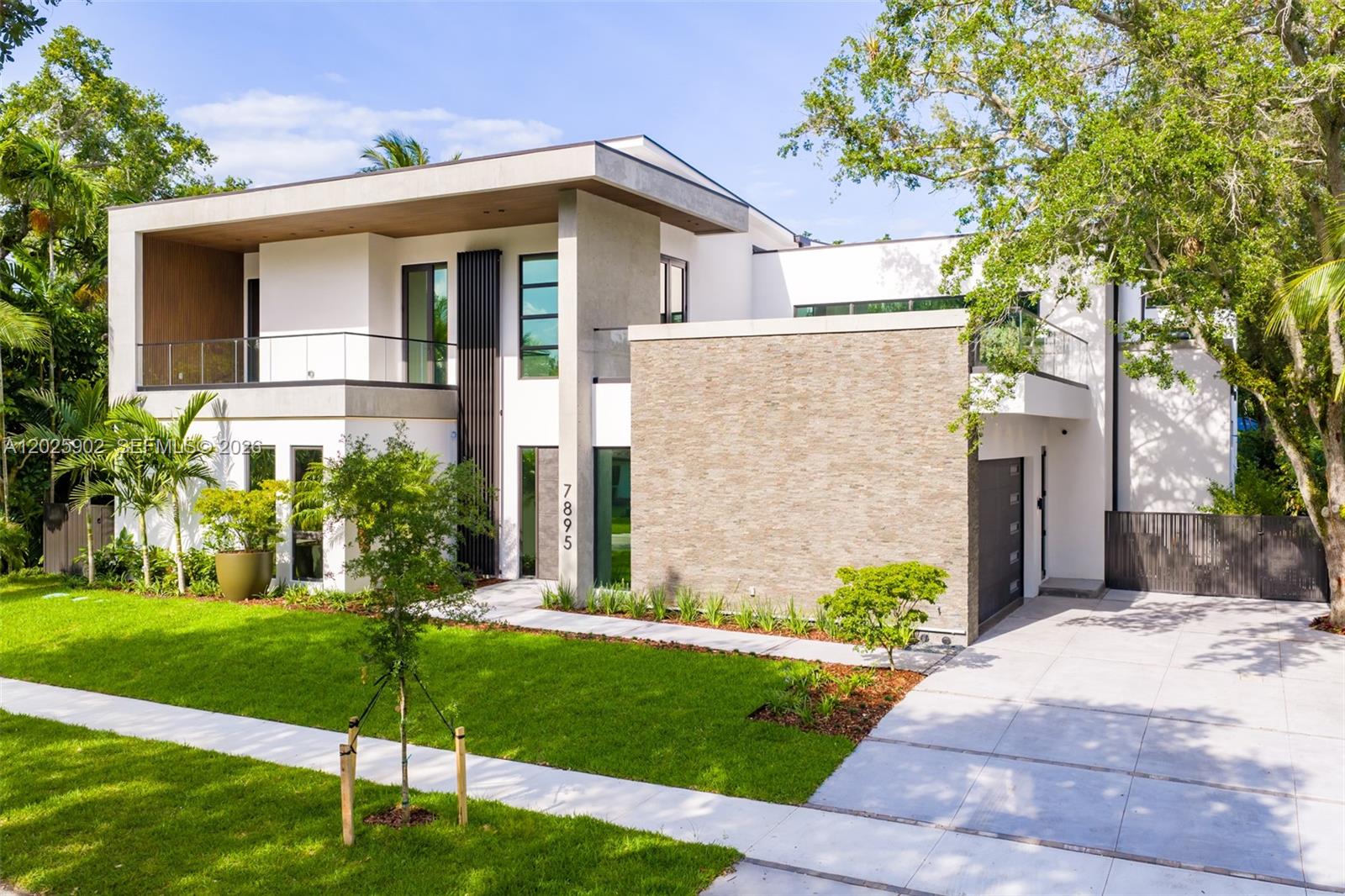 A modern two-story house features a stone facade, a glass balcony, and a concrete driveway — 7895 SW 52nd Ct, Miami FL 33143, MIAMI, FL