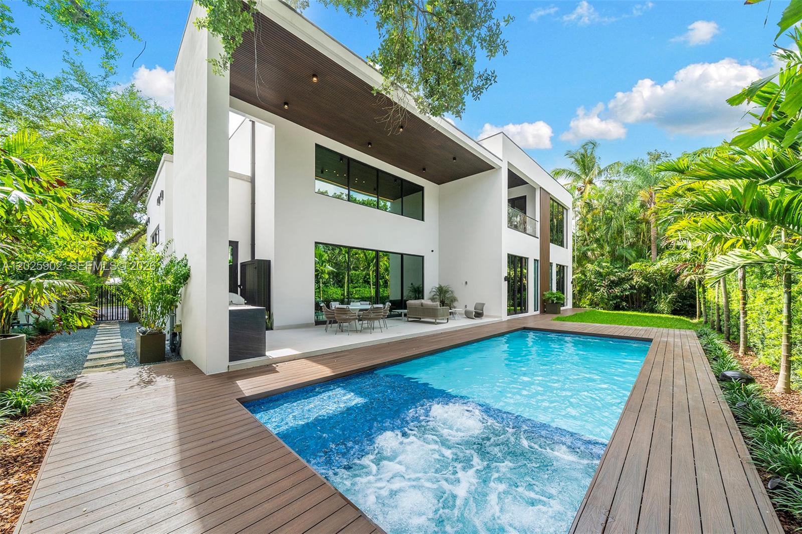 A modern two-story house features a swimming pool, wood decking, and a covered patio area — 7895 SW 52nd Ct, Miami FL 33143, MIAMI, FL