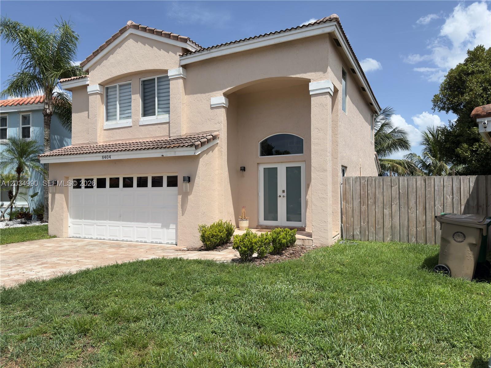 A two-story peach-colored house features a white garage door, double front doors, and a lawn — 8404 SW 42nd Ct, Davie FL 33328, DAVIE, FL
