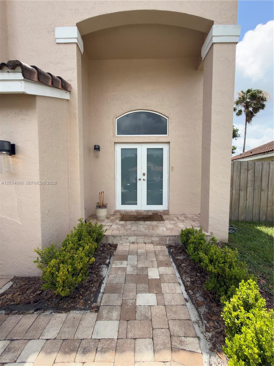 A paved walkway leads to the double glass front doors of a beige stucco home — 8404 SW 42nd Ct, Davie FL 33328, DAVIE, FL