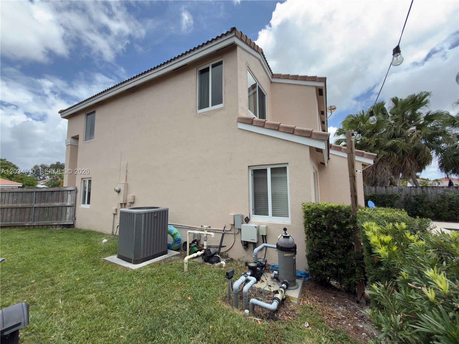 The exterior of a two-story stucco house features an HVAC unit and pool equipment — 8404 SW 42nd Ct, Davie FL 33328, DAVIE, FL
