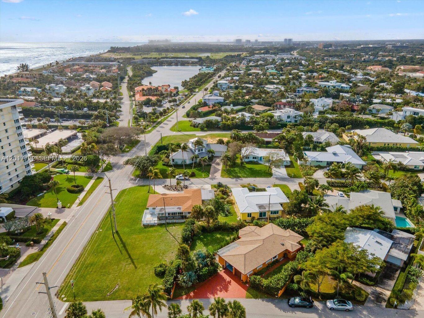An aerial view shows a residential neighborhood with houses, green lawns, and a nearby lake — xxxx Neptune Rd, Juno Beach FL 33408, JUNO BEACH, FL