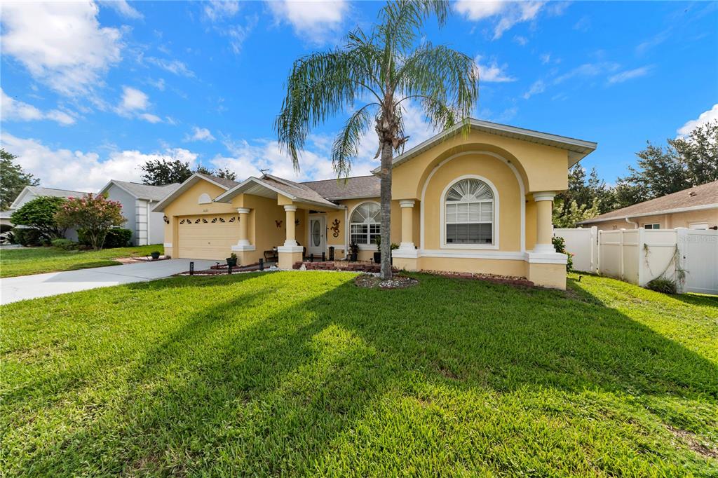 A yellow single-story house with a palm tree in the front yard — 1622 CRAZY HORSE DR, LUTZ, FL