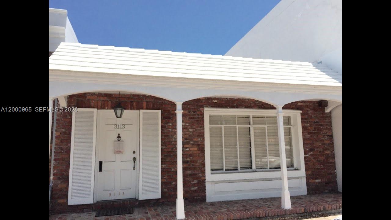 A brick exterior house features a white front door, shutters, and a covered porch — 3113 Ponce De Leon Blvd, Coral Gables FL 33134, CORAL GABLES, FL