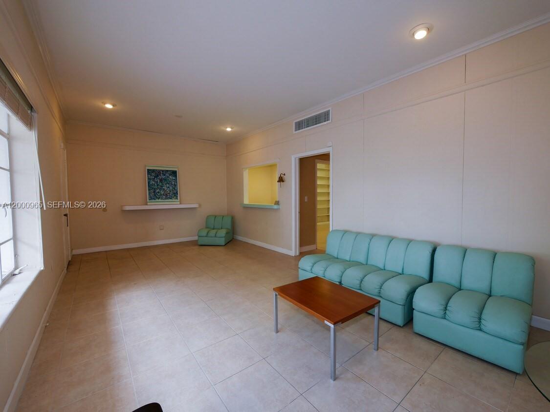 A living room features light tile floors, a teal sofa, and a pass-through window — 3113 Ponce De Leon Blvd, Coral Gables FL 33134, CORAL GABLES, FL