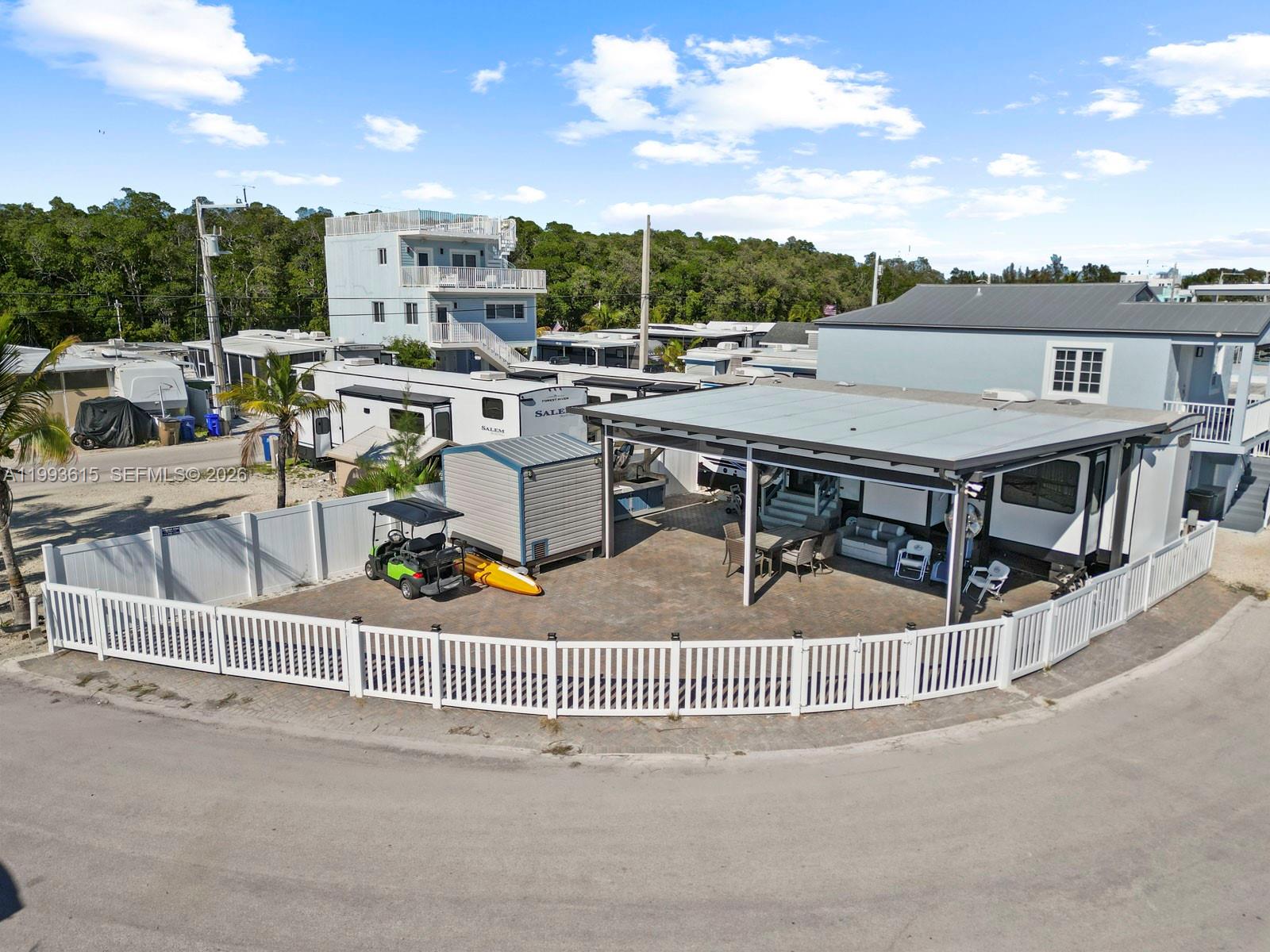 An aerial view shows a fenced patio area with a covered structure, golf cart, and RV — 325 Calusa ST 321, Key Largo FL 33037, KEY LARGO, FL