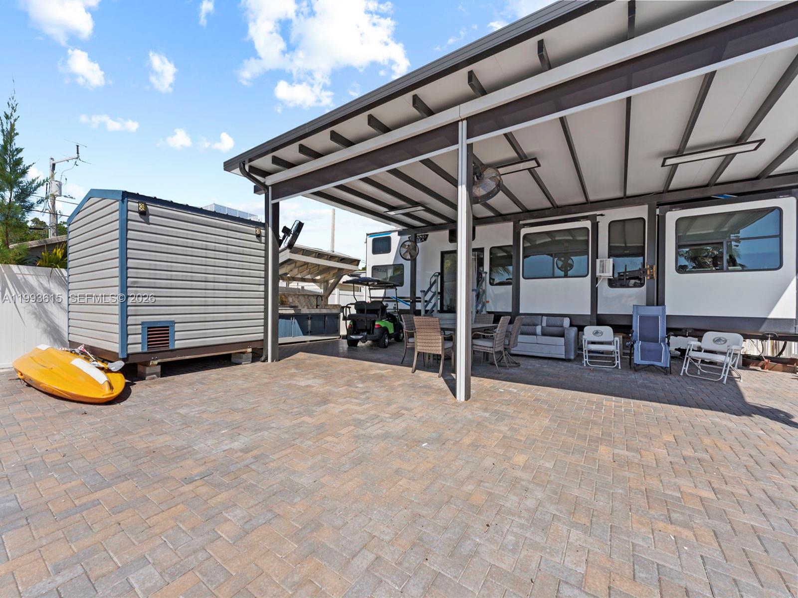 A paved patio features a covered area with outdoor furniture, a golf cart, and a shed — 325 Calusa ST 321, Key Largo FL 33037, KEY LARGO, FL