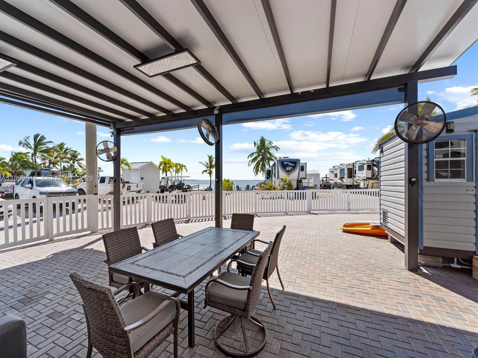 A covered outdoor patio features a dining set, ceiling fans, and a view of RVs — 325 Calusa ST 321, Key Largo FL 33037, KEY LARGO, FL